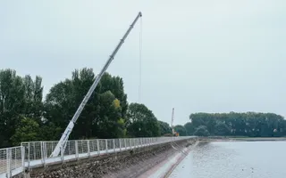Crane on the wall of reservoir on a grey wet day