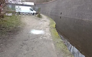 Wide shot of a canal and towpath with white van in the background