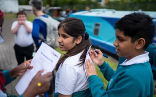 Two young explorers filling out a task sheet by the canal