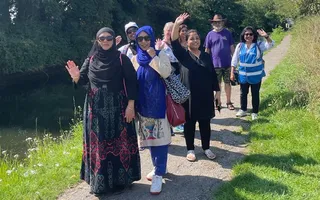 Group of people walking along a towpath on a sunny day