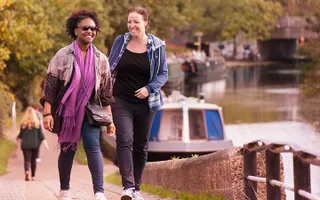 Two adults chat as they walk along the canal towpath