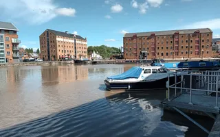 Workboat moored in Gloucester Docks with large buildings in the background