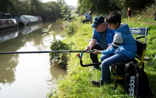 Young person with adult learning how to fish on the canal