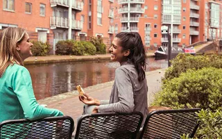 Two women eat lunch next to the canal