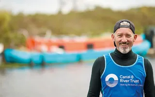 Man smiles in front of canal wearing a 'Canal & River Trust' running vest
