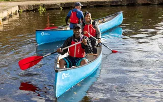 Two people in a canoe on a canal smiling at camera