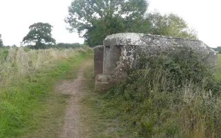 A pillbox on a canal towpath surrounded by scrubland habitat