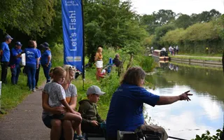 group of people sitting by the canal fishing