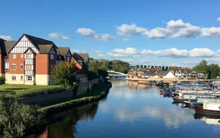 Boats moor along the River Weaver next to a large residential building