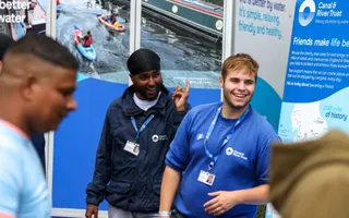 Two fundraising colleagues wearing branded clothing and lanyards talking to reservoir visitors