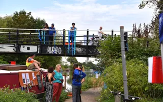 Bridge over a canal towpath with canal visitors, colleagues and boat business owners chatting