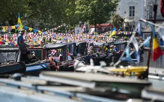 A line of colourful narrowboats moored up and covered in bunting.