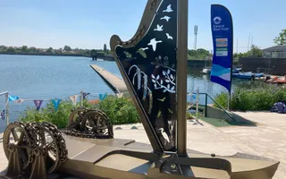 A boat statue created from gold colour materials with blue water in the background