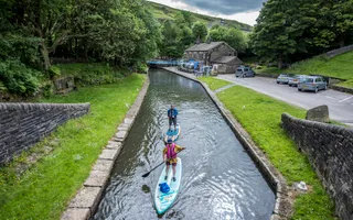 two paddleboarders, onboard near Standedge Tunnel on a cloudy day