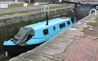 Pale blue boat midway through going up a lock on the Kennet & Avon Canal