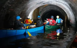 A few canoes travelling through a dark tunnel