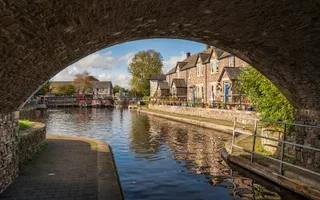 Picturesque image of Brecon Basin through a bridge. Sunny day with pretty houses next to the canal.