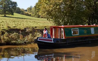 Woman leaning out of the front cratch of a boat moving along the canal