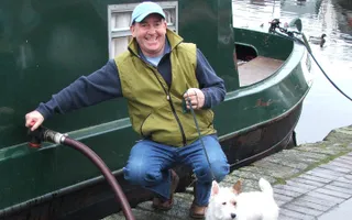 A man smiles as he pumps out his narrowboat